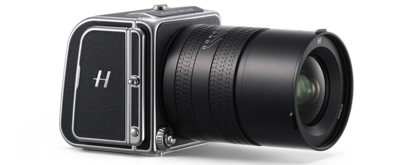 A hasselblad medium format camera with a large black lens and a metallic body, isolated on a white background.