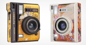 Two instant cameras from the Lomo'Instant Automat series. The camera on the left features Gustav Klimt's "The Kiss" with a black and gold design, while the camera on the right has a light color scheme with Klimt's "The Maiden" artwork.