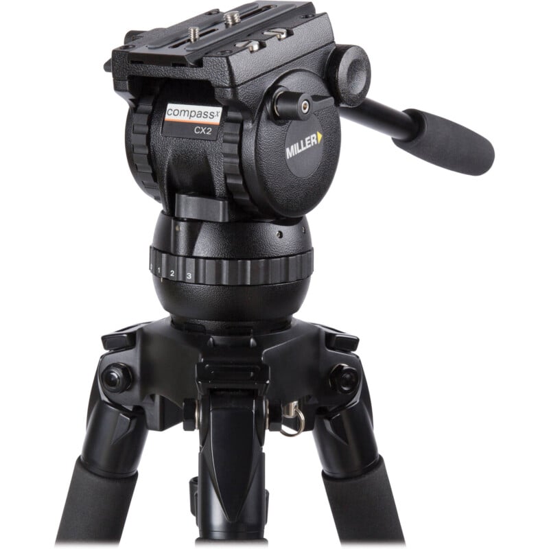 A professional black miller compassx2 video camera tripod with a fluid head and adjustable legs, set against a white background.