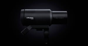 Studio photography lighting equipment, profoto pro-2 flash head, positioned against a dark background, highlighting its sleek, black cylindrical design.