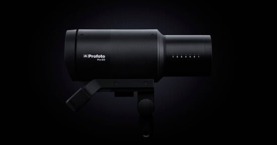 Studio photography lighting equipment, profoto pro-2 flash head, positioned against a dark background, highlighting its sleek, black cylindrical design.