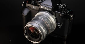A Nikon Z5 mirrorless camera with a retro-styled silver lens attached, displayed on a reflective black surface, highlighting its detailed design and controls.