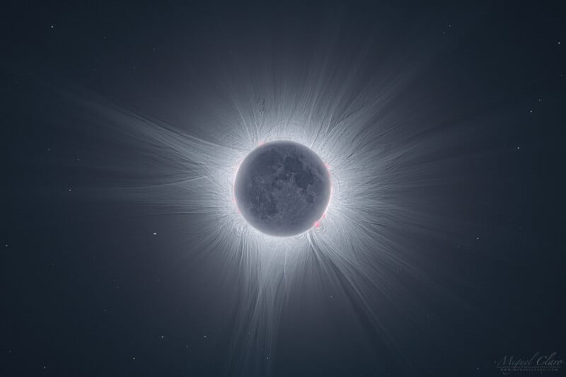 Detailed image of a solar eclipse, showing the moon completely covering the sun. The sun's corona forms a bright, glowing ring around the moon with visible rays and small prominences. Tiny stars are faintly visible in the dark sky behind.