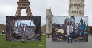 Two people stand in front of large photographs of war-torn buildings, one displayed in front of the Eiffel Tower in Paris and the other in front of the Leaning Tower of Pisa in Italy. The contrast highlights the devastation amidst iconic landmarks.