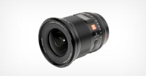 A modern black camera lens with labels indicating a focal length of 18mm and aperture of f/1.8, against a light gray background.