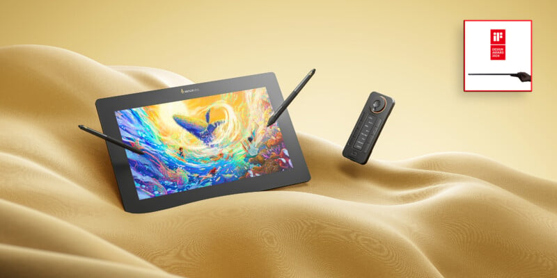 A digital tablet displaying a vibrant abstract artwork, lying on a wavy golden fabric, with a stylus and a remote control alongside. a red logo featuring an abstract black hammer is in the upper right corner.