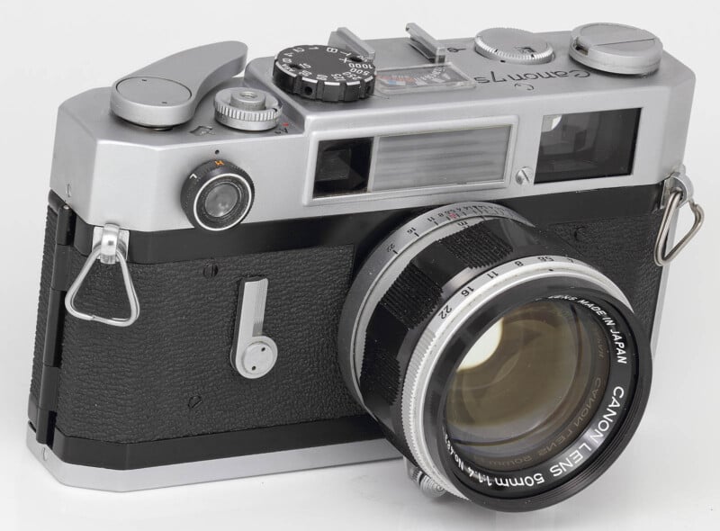 A vintage Canon 7S rangefinder camera with a Canon Lens 50mm attached. The camera has a silver and black body with various dials and controls on the top, and a leather-textured grip on the bottom half. The lens is marked with "Canon Lens 50mm 1:1.2 Made in Japan".