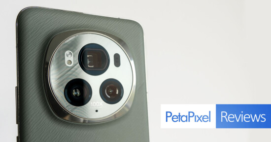 Close-up of a smartphone's camera setup featuring multiple lenses and "100x" label, against a light grey background, with a "petapixel reviews" logo in the corner.