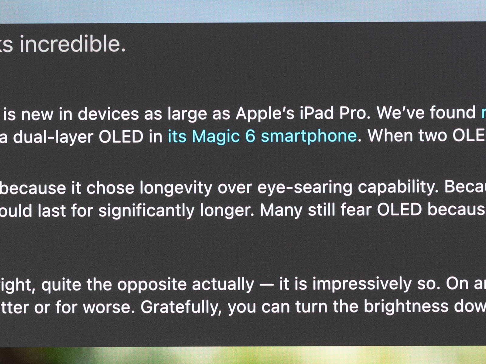 A partial screenshot of text discussing Apple's iPad Pro and a Magic 6 smartphone. The text mentions OLED technology, eye-searing capability, and display brightness, while highlighting longevity and the ability to adjust brightness.