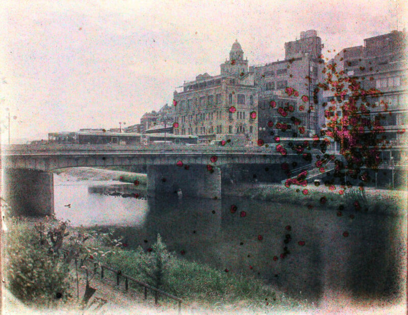 Vintage-style photo of a cityscape featuring a bridge over a river with buildings in the background, overlayed with colorful splashes resembling flower blooms.