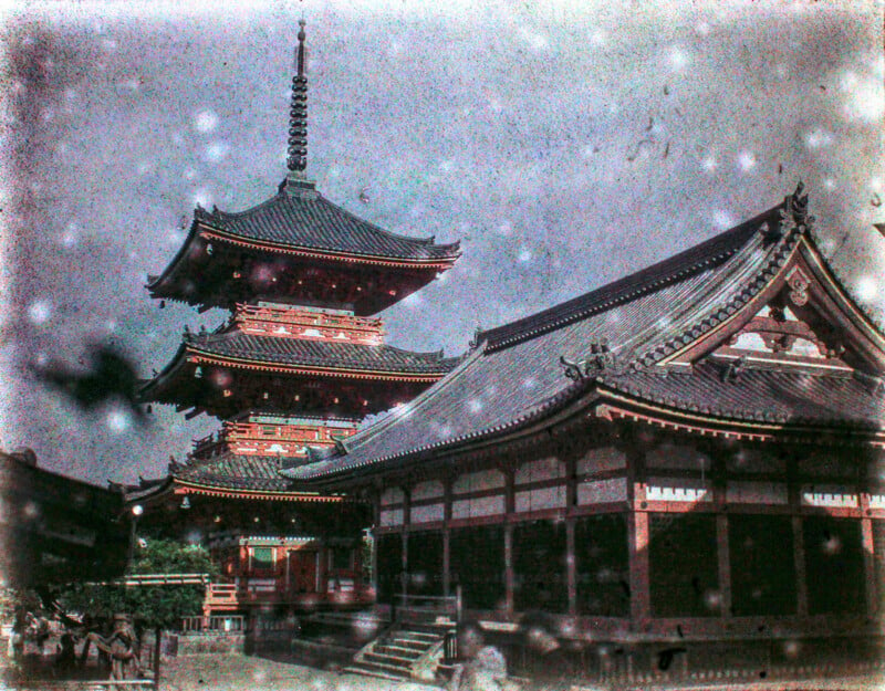Vintage-style photo showing an ancient japanese pagoda next to traditional wooden buildings, with snowflakes gently falling around the serene, architectural scene.