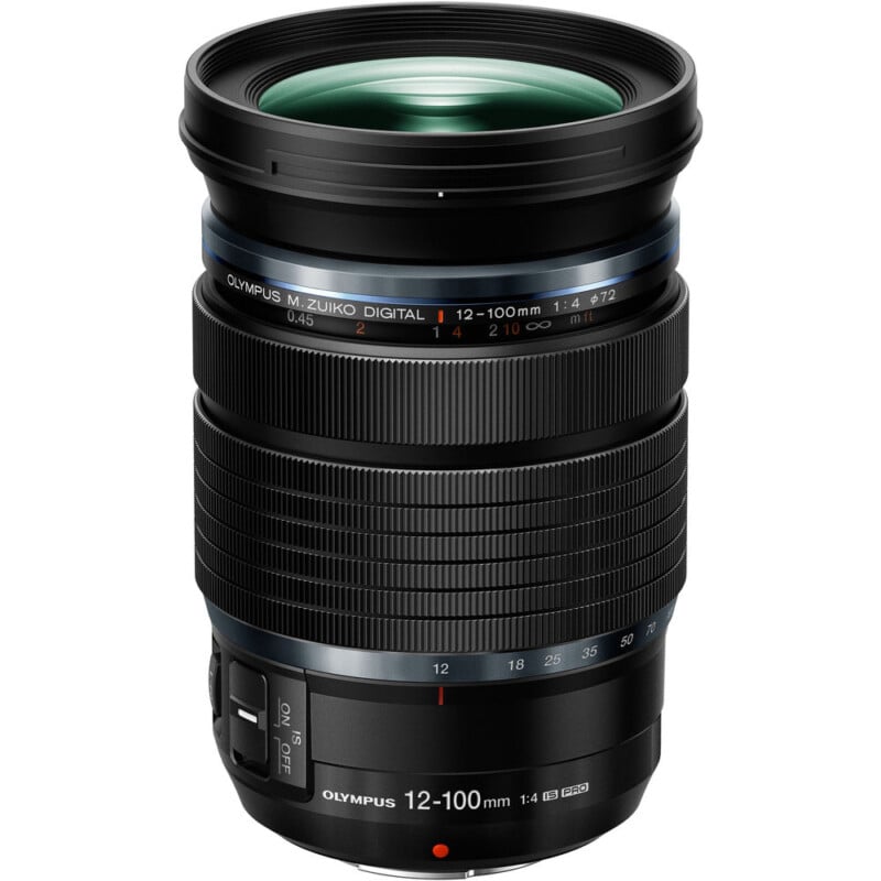 A photo of an olympus m.zuiko digital camera lens, 12-100mm f4.0, with zoom range markings and a prominent green reflective front element.