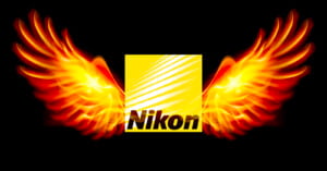 The Nikon logo, featuring stylized white text against a yellow background, is flanked by a pair of vivid, fiery orange wings on a black background.