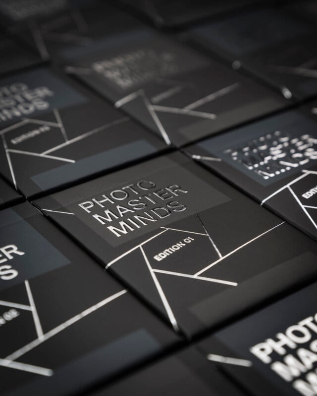 A close-up shot of neatly aligned black boxes with silver text that reads "Photo Master Minds" and geometric patterns. The focus is sharp on the central box.
