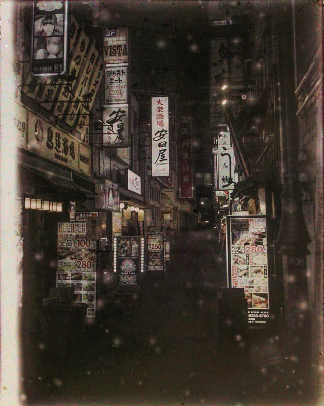 A moody, vintage-style image of a narrow tokyo alley at night, filled with brightly lit signs and banners advertising various businesses. the photo has a grainy, sepia tone adding to its atmospheric quality.