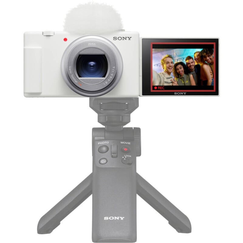 A sony camera mounted on a tripod, with its flip screen displaying a photo of three young adults smiling and posing together.