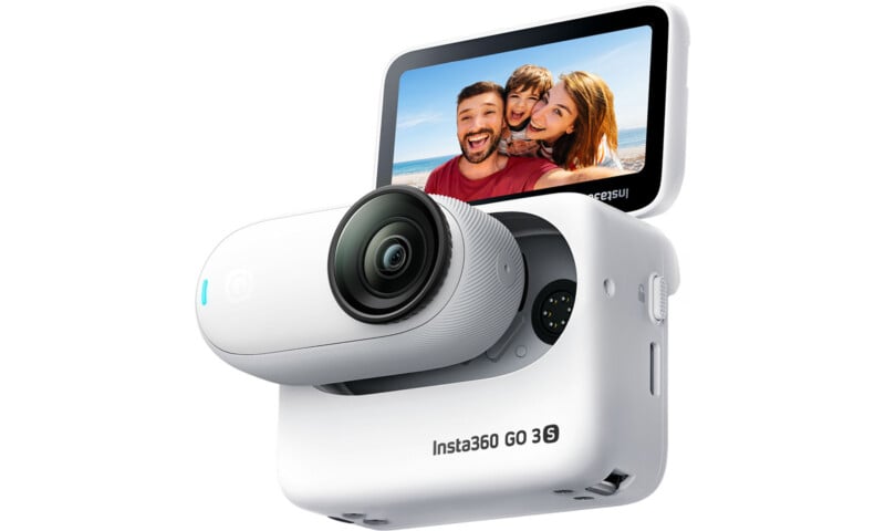 A white Insta360 GO 3 action camera is shown mounted on its charging case with its round lens facing forward. The case has a screen displaying a smiling group selfie of two adults and a child, with the text "Insta360 GO 3" on the side of the case.