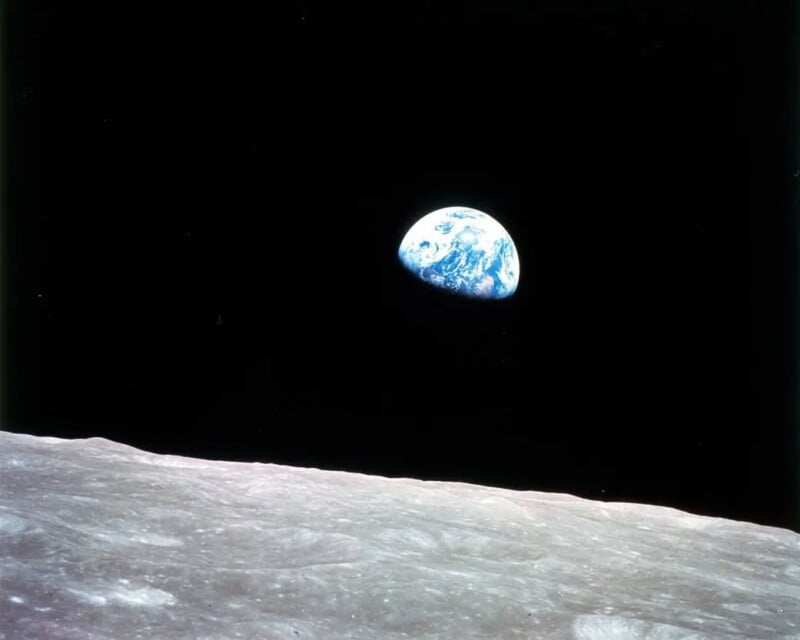 Een weergave van de aarde die boven de maanhorizon uitsteekt, gezien vanuit de ruimte.  Het oppervlak van de maan bevindt zich op de voorgrond, een rotsachtige, kraterachtige formatie, terwijl de aarde op de achtergrond staat, verlicht tegen de donkere achtergrond van de ruimte.