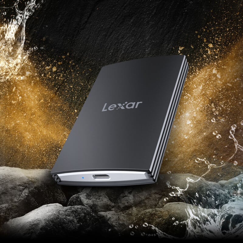 A sleek, black Lexar external hard drive is depicted against a rugged, rocky background with splashes of water around it. The hard drive's minimalist design features a single visible USB port. The imagery suggests durability and reliability even in harsh conditions.