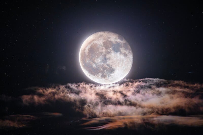 A full moon illuminates the night sky, surrounded by twinkling stars. Wispy clouds partially obscure the moon's lower section, adding a touch of mystique to the celestial scene.