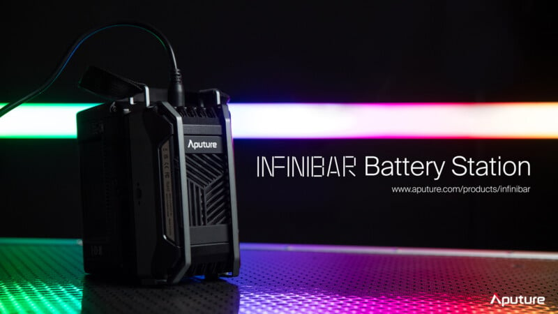 A sleek Aputure INFINIBAR Battery Station is positioned on a surface with a colorful, blurred light strip in the background. The text "INFINIBAR Battery Station" and a URL for more information are displayed on the right.