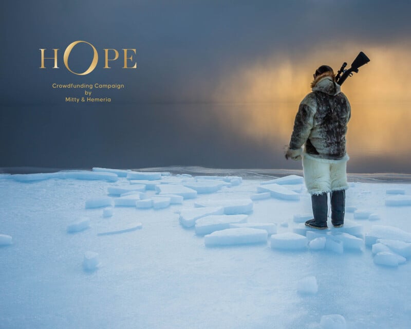 An individual dressed in warm, fur-lined clothing stands on an icy surface, looking towards a misty horizon during sunset. The word "HOPE" and the text "Crowdfunding Campaign by Mitty & Hemeria" are displayed in the upper left corner. The person carries a rifle on their back.