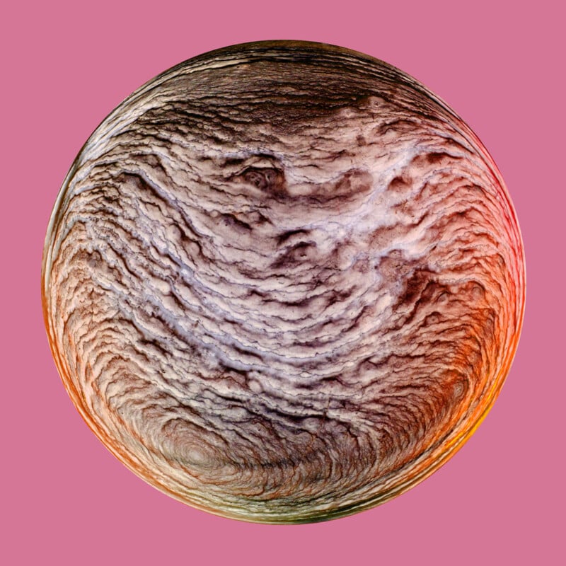 An abstract, textured circular design resembling a planet’s surface or a clay sculpture with swirling patterns and mixed shades of brown, grey, and hints of reddish-orange. The background is a solid pink color.