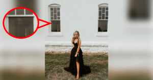 A woman in a long black dress stands on grass in front of a white building with large windows. There is a red circle with an arrow pointing to one window, highlighting a shadowy figure behind it.