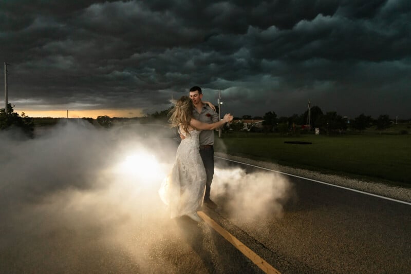a couple dance in the road beneath a thunderstorm