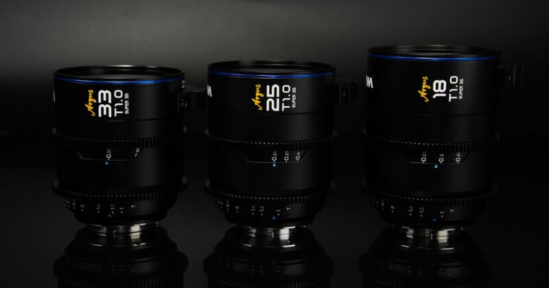 Three camera lenses are displayed against a dark background. From left to right, the lenses are labeled 30mm, 50mm, and 18mm, with T1.0 written on each. The lenses are black with blue accents, and numerals marking focal distances are visible on each lens.