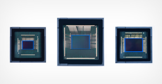 Three microchips are displayed side by side against a plain, white background. Each has a similar square-shaped central processing unit with intricate wiring visible around the perimeter. The chips vary in size, with the middle one being the largest.
