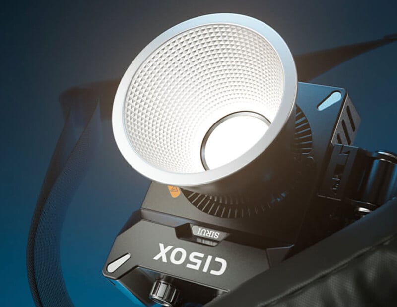 A close-up image of a professional studio light with a hexagonal reflector. The light is branded "GODOX" and is mounted on a stand. The background is a gradient of blue tones.