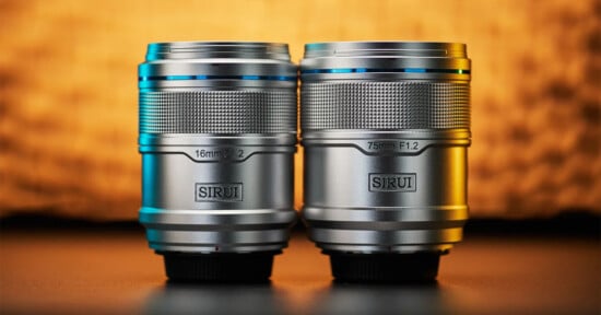 Two silver camera lenses from the brand Sirui are placed side by side on a dark surface against a warm, blurred background. The lens on the left is labeled 16mm F1.2, and the one on the right is labeled 75mm F1.2.