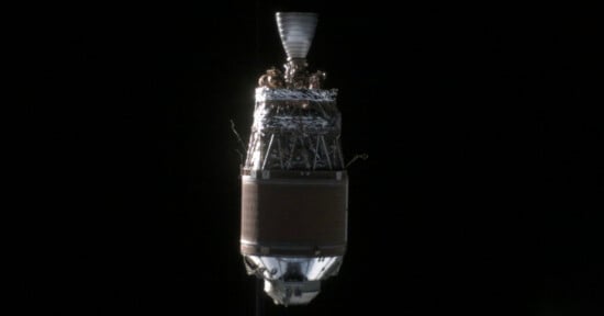 Image of a spacecraft stage with a conical upper section, metallic surface, and complex structures. The background is the blackness of space, emphasizing the details and engineering of the spacecraft stage. The image captures the intricate design and technical components.