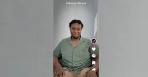 A seated man with short, curly hair and a casual green shirt smiles at the camera in a TikTok video. The screen shows typical TikTok interface elements, including icons for likes, comments, and favorites on the right side, with "Following | For you" text at the top.