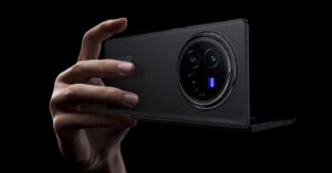 A hand holds a sleek, black Vivo smartphone, showcasing a prominent circular rear camera module with multiple lenses. The camera is branded with "ZEISS" indicating advanced optics. The background is black, emphasizing the phone's design.