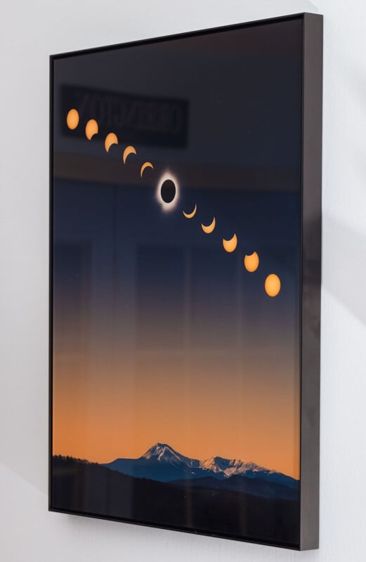 A framed photograph shows the progression of a solar eclipse over a mountainous landscape during sunset. The sequence depicts the transition from a partial eclipse to a total eclipse and back to a partial, set against a gradient sky from dark blue to bright orange.