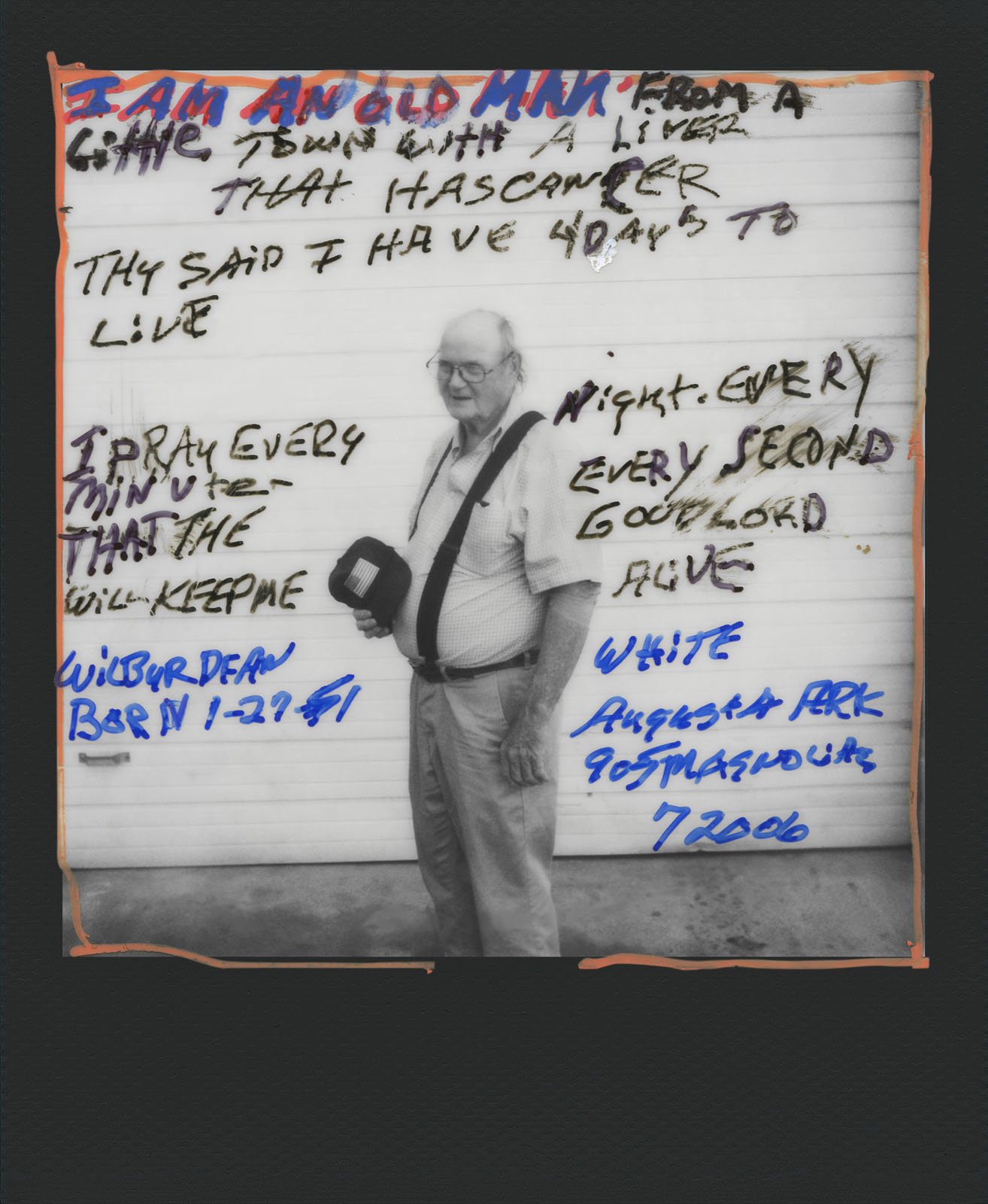 A black-and-white photograph of an elderly man with a camera bag over his shoulder. He stands in front of a handwritten note on a whiteboard describing his battle with cancer and limited time to live. The note mentions prayer and addresses in blue and red ink.