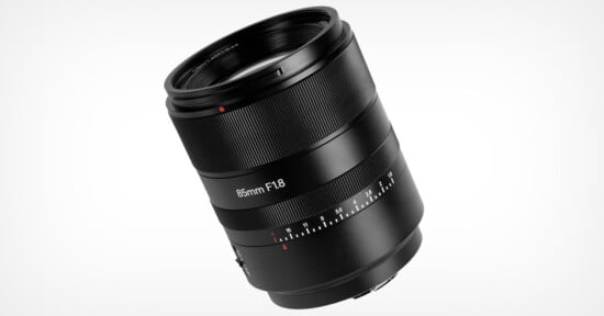 A black 85mm F1.8 camera lens with a smooth exterior and various control rings, set against a white background. The lens features markings for focal length and aperture settings.