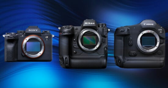 Three digital cameras are displayed against a blue wavy background. From left to right, the cameras are models from Sony, Nikon, and Canon. Each camera has a visible lens mount, showcasing their distinct designs and features.
