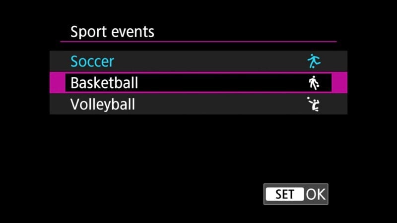 A black screen displays a sports event selection menu with three options: Soccer, Basketball, and Volleyball. Soccer is highlighted in blue with an icon of a person kicking a ball, Basketball has a person dribbling a ball, and Volleyball has a person hitting a ball. A "SET" button is at the bottom right.