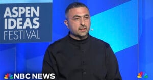 Mustafa Suleyman wearing glasses and a black shirt delivers a speech at the Aspen Ideas Festival. The backdrop features the festival's logo. The NBC News logo is displayed at the bottom left corner of the image.