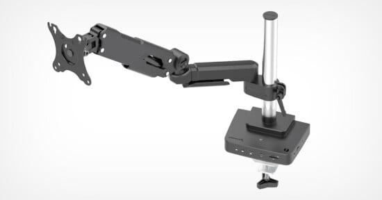 An adjustable, black and silver desk mount designed for holding a computer monitor. The mount features articulated arms and a clamp base for attachment to a desk. The base includes multiple ports for connectivity, including USB and audio.