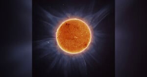 A detailed, high-resolution image of the sun with visible swirling plasma and sunspots. The sun's corona is seen emitting a glowing aura against a dark background, highlighting the solar activity and energy emanating from the star.
