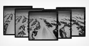 A series of overlapping aerial photographs depicts a snowy mountain range with rugged peaks and valleys. The images, positioned in a slight arc, showcase a vast expanse of snow, ice, and rock, suggesting a remote and cold landscape.