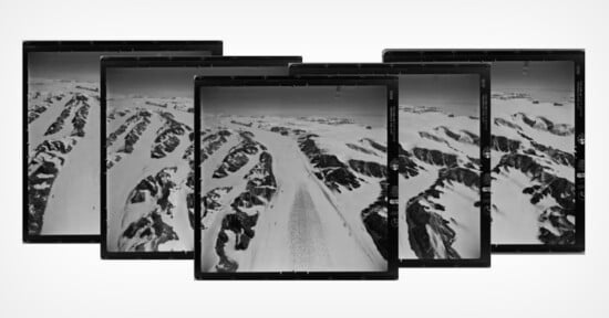 A series of overlapping aerial photographs depicts a snowy mountain range with rugged peaks and valleys. The images, positioned in a slight arc, showcase a vast expanse of snow, ice, and rock, suggesting a remote and cold landscape.