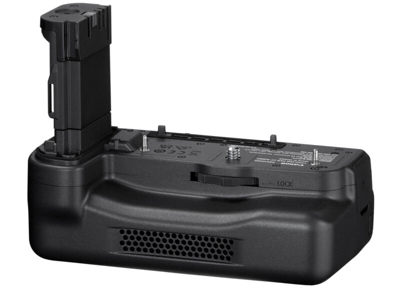 An image of a black camera battery grip, with a vertical attachment slot and various buttons and switches. The battery grip has textured surfaces and a locking mechanism, designed to provide additional battery life and better handling for photographers.