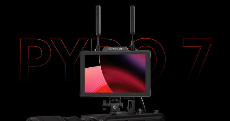 A Holliland video monitor with two antennas is mounted on a camera. The monitor screen displays a red and black abstract background. The text "PYRO 7" is faintly visible in the background. The overall color scheme of the image is dark.