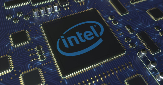 Close-up of a computer motherboard with an Intel processor in the center. The Intel logo is prominently displayed on the black processor, surrounded by numerous electronic components and circuits on the blue motherboard.