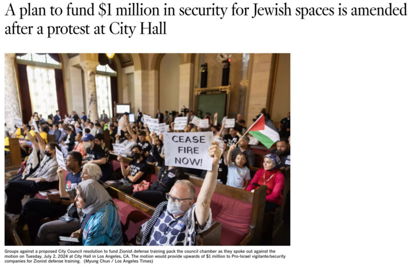 A diverse group of people are protesting inside a government chamber. Signs held by attendees include one that reads "CEASE FIRE NOW!" and a Palestinian flag. The caption reports that the protest is against a plan by the City to fund security for Jewish spaces.